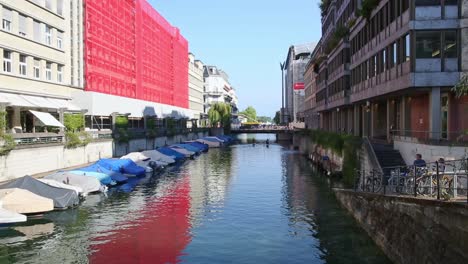 Pequeños-Botes-Cubiertos-En-El-Río-Y-La-Ciudad-De-Zúrich-Paisaje-Tranquilo-De-La-Calle-Iluminada-Por-El-Sol