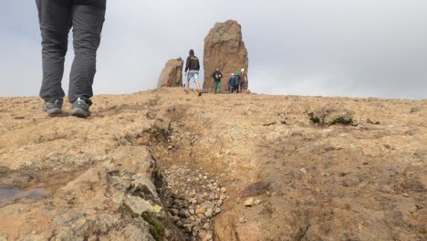 Las-Palmas-de-Gran-Canaria,-Spain---January-24,-2023:-Hiking-group-ascending-to-Roque-Nublo-duroing-a-misty-morning-in-Gran-Canary-Island,-Spain