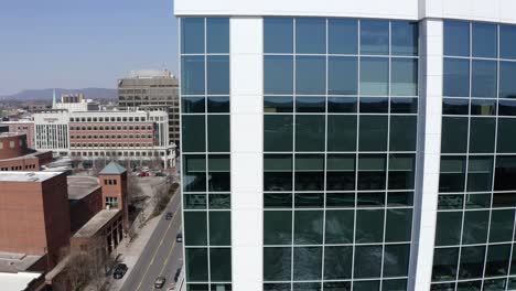 Aerial-reveal-of-main-street-in-Greenville,-South-Carolina-from-behind-glass-Bank-of-America-skyscraper