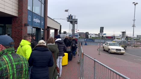 Cámara-Lenta-De-Turista-Con-Máscara-Facial-Esperando-En-Fila-Frente-Al-Ferry-Que-Navega-A-La-Isla-De-Norderney,-Alemania-Durante-El-Día-Nublado-De-Otoño