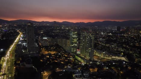 Ascending-aerial-view-of-the-Arcos-Bosques-shopping-complex,-dusk-in-Mexico-city
