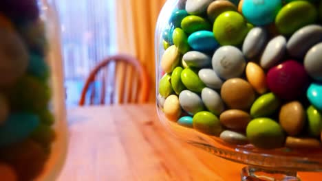 Glass-jar-filled-with-colourful-crisp-coated-chocolate-candies-slow-pull-back-reveal