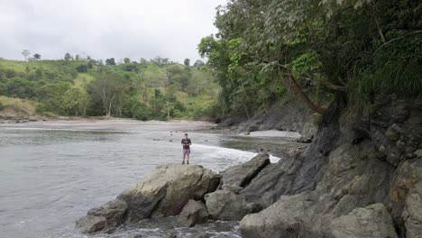 Young-man-looking-out-over-the-secluded-and-tropical-Playa-La-Vaca-near-Quepos,-Costa-Rica