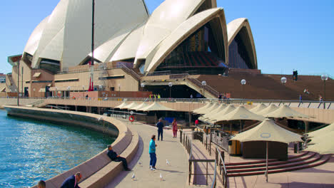 La-Gente-Pasa-El-Rato-En-El-Paseo-Marítimo-Con-Café-Cerca-De-La-ópera-De-Sydney-En-Nsw,-Australia