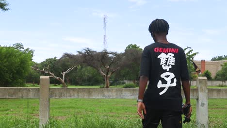 Slow-motion-shot-of-a-boy-in-black-t-shirt-walking-towards-the-fence-in-the-park-and-exploring-the-environment-around-the-park-at-Harare,-Zimbabwe