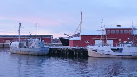 Panning-across-ships-and-boats-moored-at-dock-and-pier-during-polar-night-above-the-arctic-circle-in-Narvik,-northern-Norway