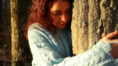 young-red-hair-caucasian-girl-hugging-a-tree-in-the-woods-at-sunset,-zoom-in-close-up-shot
