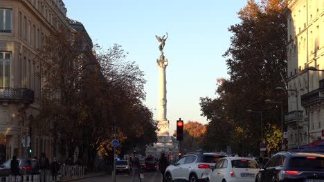 Avenida-30-De-Julio-Con-Vistas-A-La-Columna-Del-Monumento-Girondins-Con-Tráfico-De-Vehículos-Y-Personas-En-Un-Día-De-Otoño,-Tiro-De-Mano