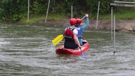 Two-people-sit-on-canoe-and-paddle-down-a-river