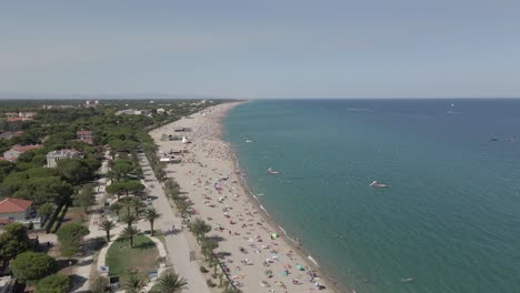 Crowded-beach-flyover-on-French-Mediterranean-sea-coast,-sunny-day