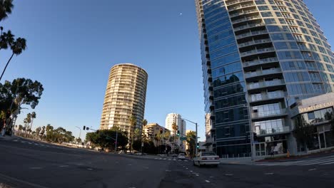 Driving-along-the-iconic-streets-of-Long-Beach,-California-with-the-streets-lined-with-palm-trees-on-a-clear-blue-day