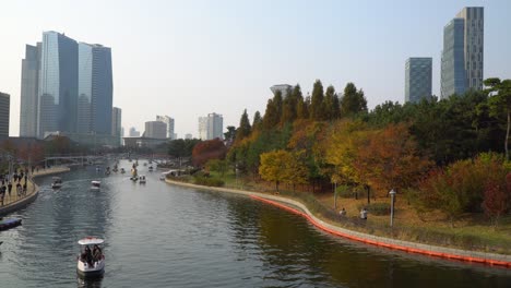 Urban-city-skyline-in-Songdo-Central-Park-in-Incheon-in-November,-Lake-and-Autumn-foliage-with-Skyscrapers-on-background