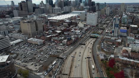 Aerial-View-of-Interstate-Highway-Traffic-and-Downtown-Philadelphia-Buildings-on-Dark-Autumn-Day,-Revealing-Drone-Shot