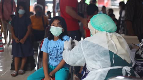 Yogyakarta,-Indonesien---20.-Dezember-2021:-Ein-Grundschulmädchen,-Das-Eine-Maske-Trägt,-Erhält-Den-Covid-19-impfstoff