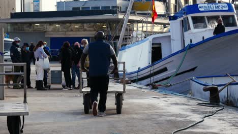 Schwarzer-Mann-Mit-Musikhelmen,-Der-Rückwärts-Mit-Einem-Leeren-Karren-Im-Hafen-Von-Santa-Pola-Läuft