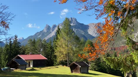 Hermoso-Paisaje-Otoñal-Cerca-De-Scharnitz-En-Austria-Con-Una-Cabaña-árboles-Coloridos-Y-Altas-Montañas-Karwendel-En-El-Fondo,-Tiro-Inclinado-De-Cerca