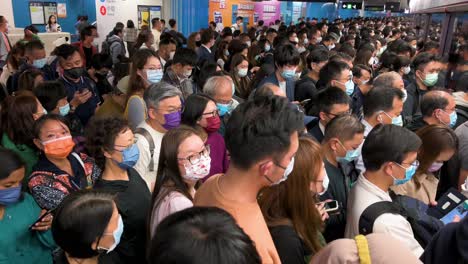 Menschen-Mit-Gesichtsmasken-Warten-Während-Der-Hauptverkehrszeit-In-Der-Schlange,-Bis-Eine-U-bahn-An-Einer-Mtr-station-In-Hongkong-Ankommt