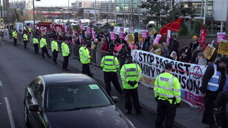 Un-Automóvil-Y-Una-Camioneta-De-La-Policía-Pasan-Junto-A-Personas-Que-Sostienen-Pancartas-Y-Pancartas-En-Una-Protesta-Antifascista-Contra-El-Racismo