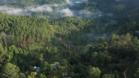 Beautiful-unique-aerial-of-the-Nine-Arch-Bridge-surrounded-by-lush-jungle-with-low-hanging-clouds,-Ella-Sri-Lanka