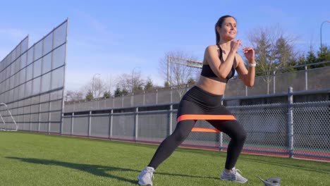 Young-female-athlete-exercising-resistance-band-walking-squats