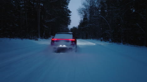 Tiro-De-Persecución-De-Drones-Del-Modelo-Naranja-Porsche-Macan-Gts-2022-Conduciendo-A-Través-De-Un-Camino-Nevado-En-El-Bosque-Al-Atardecer