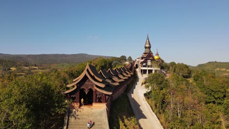 A-man-in-a-yellow-shirt-standing-at-the-door-then-two-children-arrive-and-sat-on-the-staircase-of-Wat-Somdet-Phu-Ruea,-Ming-Mueang,-Loei-in-Thailand