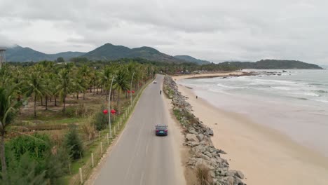 Tesla-Model-3-Fährt-Auf-Einer-Küstenstraße-Entlang-Der-Tropischen-Strandküste