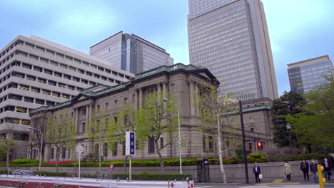 TOKYO,-JAPAN,-circa-April-2020:-people-waiting-for-signal-changing-near-protected-building,-Bank-of-Japan,-at-old-downtown-in-central-financial-district,-spring-evening