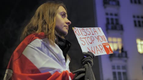 2022-Russland-Einmarsch-In-Die-Ukraine---Mädchen-Mit-Einer-Flagge-Des-Freien-Weißrusslands,-Die-Am-Ersten-Kriegstag-Bei-Einer-Antikriegsdemonstration-In-Warschau-Eine-Tafel-Mit-Einem-Slogan-Hält
