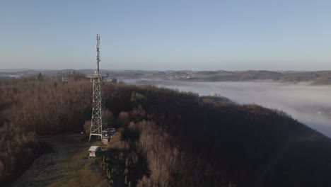 Aerial-footage-of-the-observation-tower-of-Morsbach-in-North-Rhine-Westphalia,-Germany-during-a-stunningly-foggy-sunrise