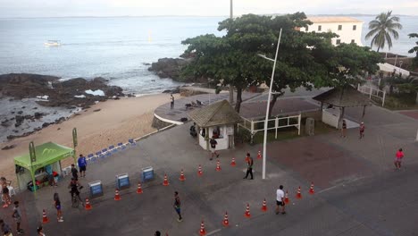 Group-Of-Athletic-People-Running-On-Coastal-Road-Near-Porto-de-Barra-Beach-In-Salvador,-Brazil
