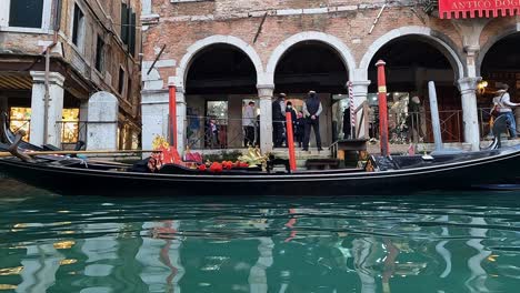 Low-angle-water-surface-pov-of-gondolas-and-gondoliers-waiting-for-tourists,-Venice-in-Italy