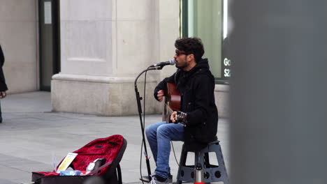 Junge-Straßenmusikanten-Spielen-Gitarre-Und-Singen-Auf-Einem-Mikrofon,-Das-Straßenkunst-Aufführt