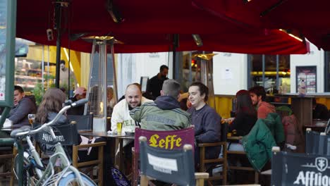 Happy-friends-meet-and-drink-in-an-open-air-cafe-terrace-downtown-city-Brussels,-Belgium---Concept-of-people,-leisure,-communication,-fun,-new-normal