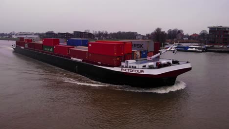 Aerial-View-Of-Factofour-Ship-Transporting-Stacked-Containers-Along-River-Noord