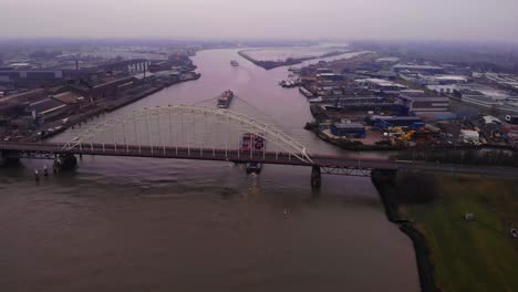 Vista-Aérea-De-Los-Buques-De-Carga-Maas-Y-Fps-Rijn-Que-Pasan-Por-Debajo-De-Brug-Over-De-Noord-En-Una-Tarde-Nublada