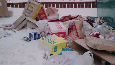 Trash-and-Garbage-Thrown-Outside-of-The-Garbage-Container-With-Snow-In-The-Winter---Handheld-Wide-Shot