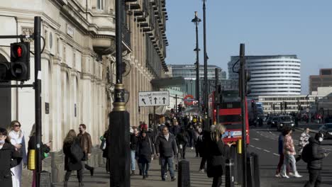 A-busy-public-sidewalk-which-runs-adjacent-to-Bridge-Street-in-Westminster,-people-going-about-their-day-walking-to-their-destination,-London,-England