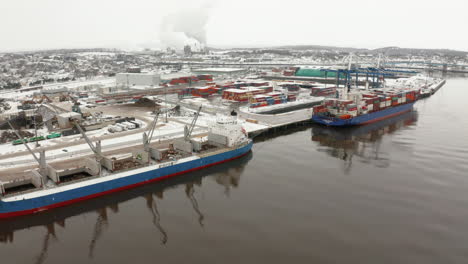 Luftaufnahme-Von-Zwei-Großen-Frachtern,-Die-An-Einem-Verschneiten-Wintertag-Im-Hafen-Angedockt-Sind