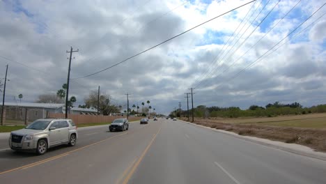 POV-driving-on-a-four-lane-road-and-turning-into-a-gated-community-in-the-Rio-Grande-Valley-in-Texas-on-a-cloudy-day