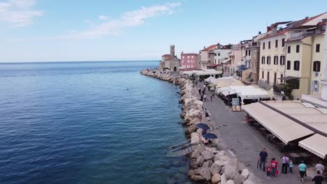 Piran,-Istria,-Eslovenia---Vista-Aérea-De-Drones-Del-Bulevar-Con-Turistas-A-Pie,-Restaurantes-E-Iglesia