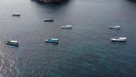 Impresionante-Vista-Aérea-Vuelo-Lentamente-Circular-Toma-De-Drones-De-Barcos-De-Pesca-Flotando-En-Agua-Azul-En-La-Playa-De-Crystal-Bay-En-Instagram-Influenciador-Isla-Nusa-Penida