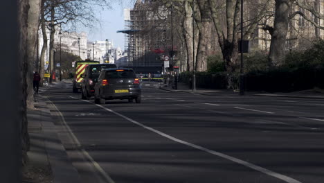View-Beside-Cycle-Lane-And-busy-Millbank-road-in-Westminster,-vehicles-passing-by-on-their-daily-commute,-in-the-distance-a-building-covered-in-scaffolding-and-under-construction,-London,-UK