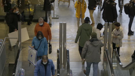 Camera-follows-a-man-as-he-rides-up-an-escalator-and-walks-off