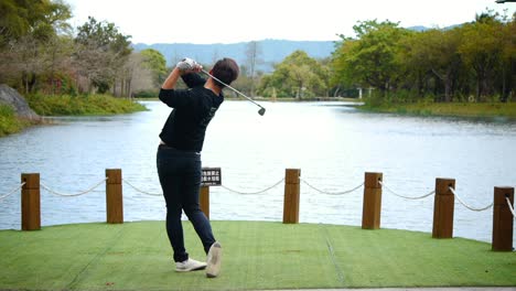 Asiatischer-Mann-Schwingt-Golfschläger-Und-Schlägt-Golfball-In-Einen-Wunderschönen-See-Mit-Wunderschönem-Waldblick