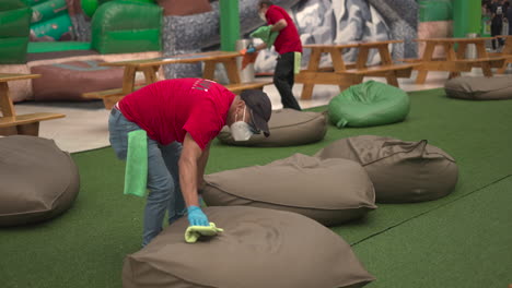 man-in-mask-cleaning-chairs-next-to-inflatables-in-mall