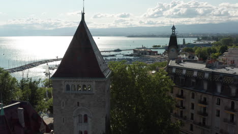 Drone-flying-between-historical-buildings-in-downtown-Lausanne,-Switzerland-towards-a-large-harbor-at-lake-Geneva