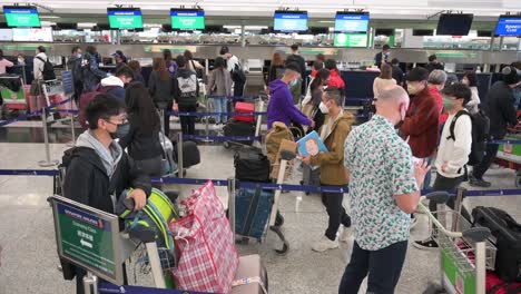 Los-Pasajeros-Esperan-En-Fila-Para-Una-Aerolínea-De-Mostrador-De-Facturación-En-El-Aeropuerto-Internacional-Chek-Lap-Kok-En-Hong-Kong,-China