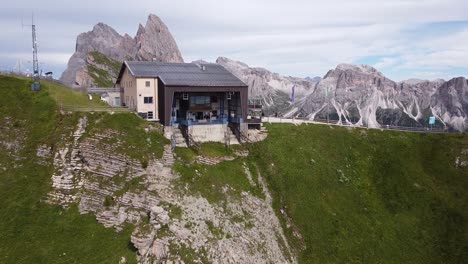 Seceda-En-Val-Gardena,-Urtijei,-Tirol-Del-Sur,-Alpes-Italianos,-Dolomitas,-Italia---Vista-Aérea-De-Drones-De-La-Estación-Del-Teleférico,-Valle-Verde-Y-Pico-De-La-Montaña