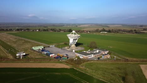 Drone-shot-flying-towards-a-large-satellite-dish-in-rural-countryside